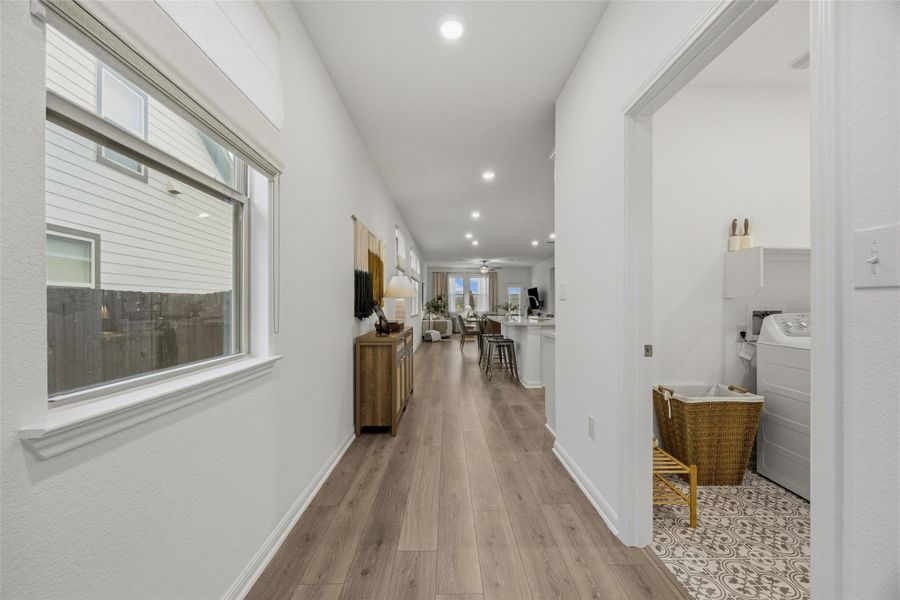 Long hallway with wood-finish flooring extending into an open-concept living space