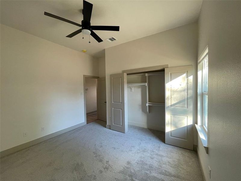 Secondary bedroom with ceiling fan, lofted ceiling, light carpet, and a closet