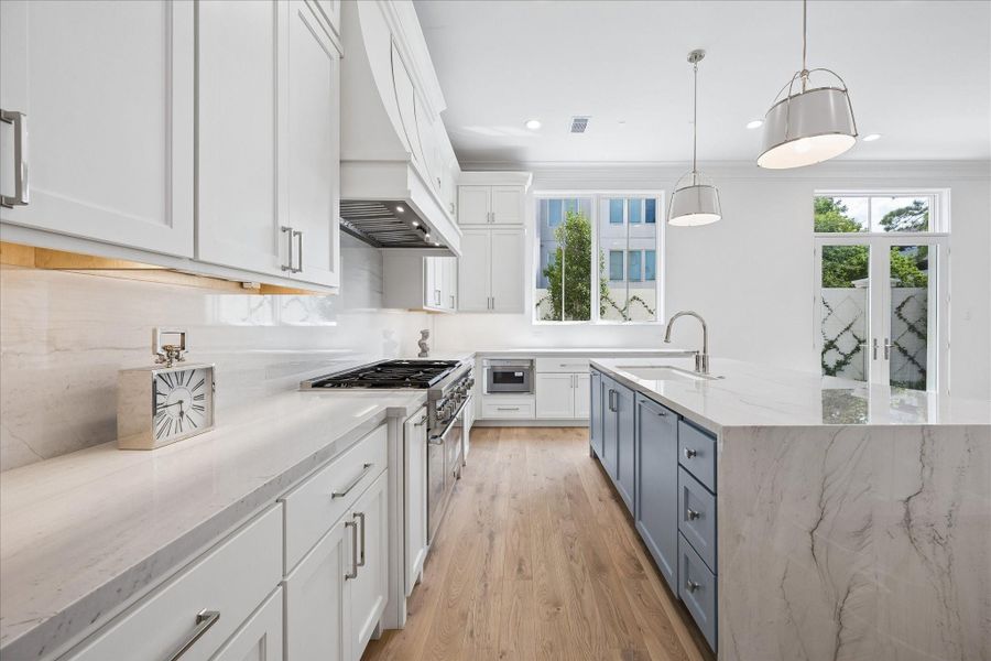 Kitchen features custom Benedettini cabinetry throughout, including upgraded decorative hood and cabinet fronts for dishwasher, refrigerator, and freezer.