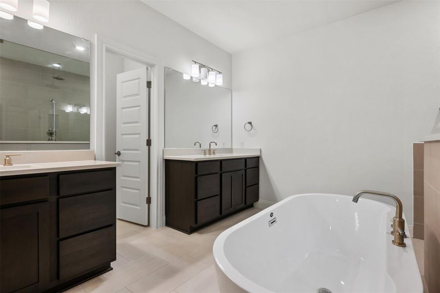 Bathroom featuring a freestanding bath, a stall shower, two vanities, and light tile patterned flooring Bathroom featuring a freestanding bath, a stall shower, two vanities, and light tile patterned flooring