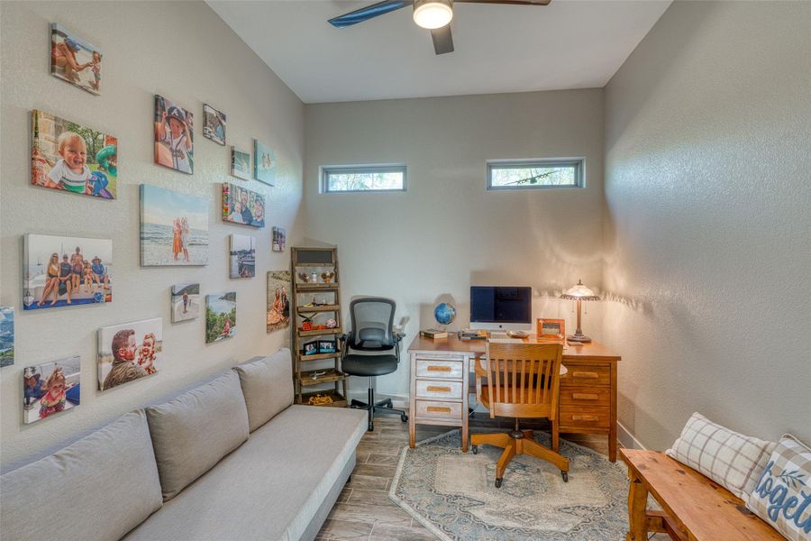 Home office with a textured wall, wood finished floors, and ceiling fan