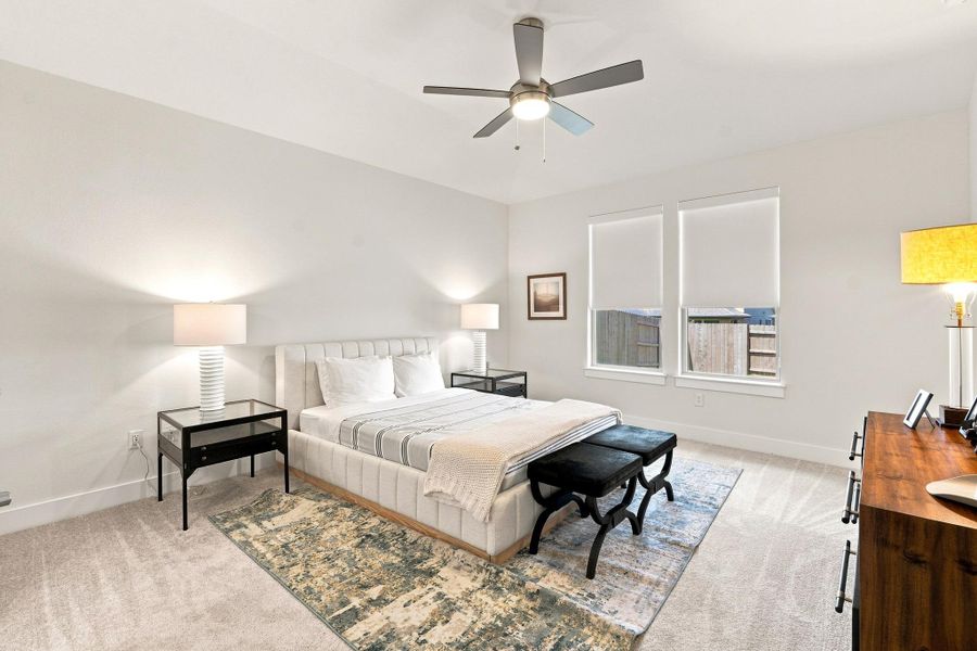 Primary bedroom retreat featuring a vaulted ceiling, modern ceiling fan, plush carpet, and double doors leading into the en-suite bath. Primary bedroom retreat featuring a vaulted ceiling, modern ceiling fan, plush carpet, and double doors leading into the en-suite bath.
