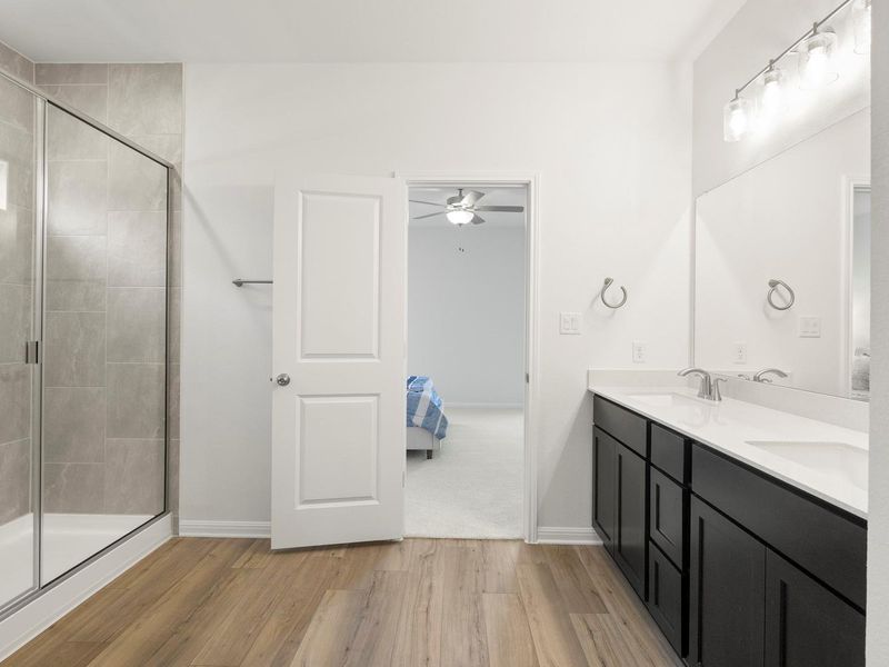 A well-appointed primary bathroom showcases a dual vanity and a contemporary glass-enclosed shower.