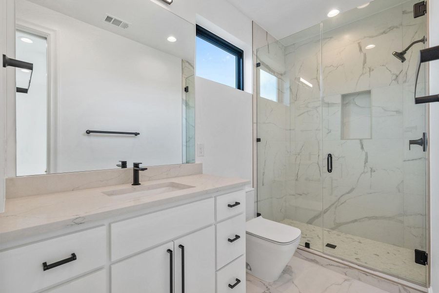 Bathroom featuring a marble finish shower, vanity, recessed lighting, and light marble finish flooring