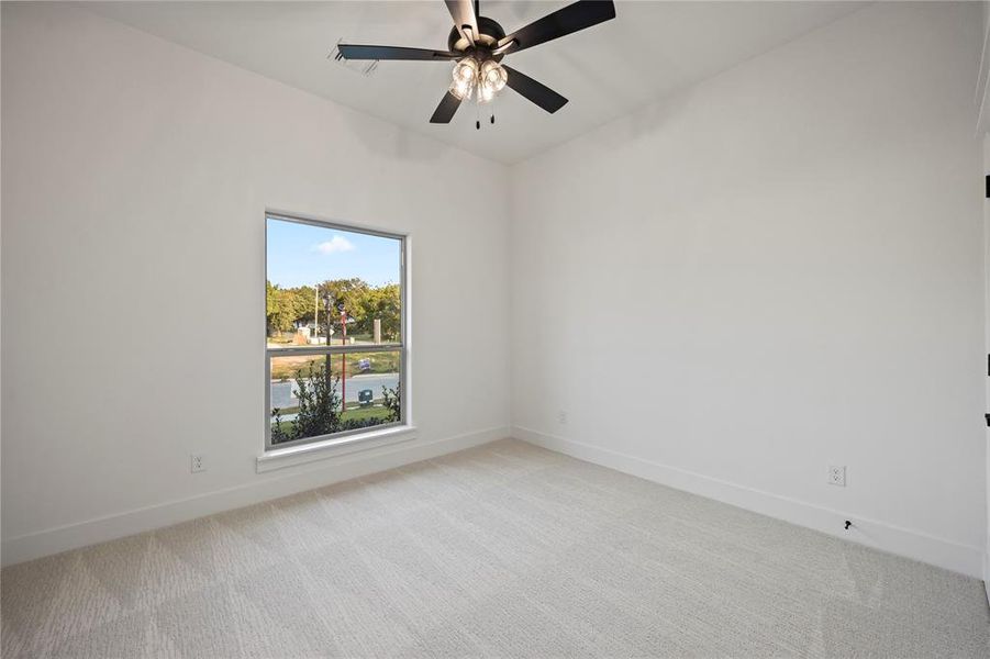 Empty room featuring light carpet and a ceiling fan