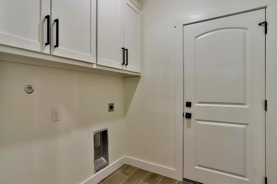 Washroom with cabinets, hookup for an electric dryer, and light hardwood / wood-style floors