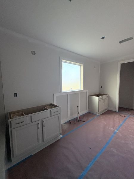 Built-in cabinetry with modern hardware, window with trim, and wainscoting detailing