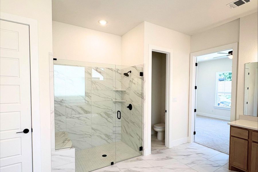 Marble-patterned tile floors and a glass-enclosed shower create a refined primary bath retreat. Marble-patterned tile floors and a glass-enclosed shower create a refined primary bath retreat.
