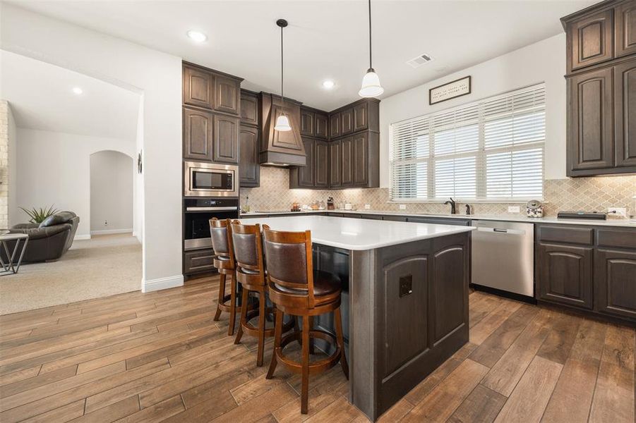 Kitchen with a center island, dark brown cabinetry, and stainless steel appliances Kitchen with a center island, dark brown cabinetry, and stainless steel appliances