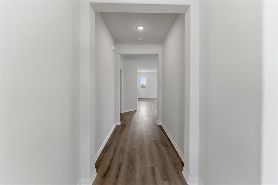 Hallway featuring wood-finish flooring, recessed lighting, white baseboards, and neutral wall finishes