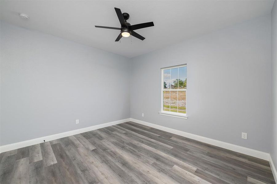 Unfurnished room with wood finished floors and a ceiling fan Unfurnished room with wood finished floors and a ceiling fan