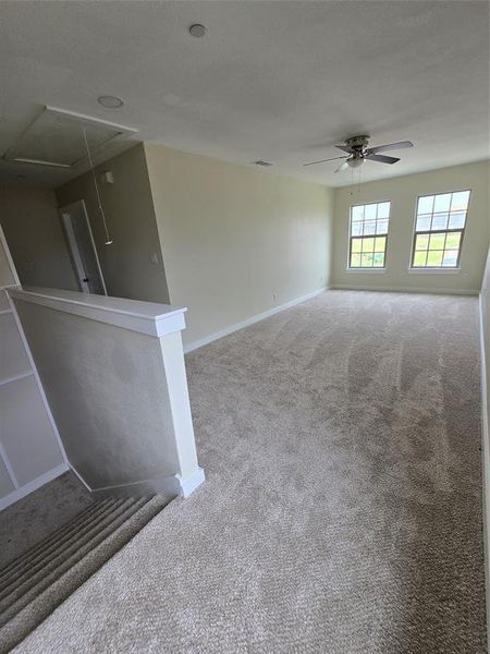 Unfurnished room featuring attic access, carpet floors, ceiling fan, and baseboards