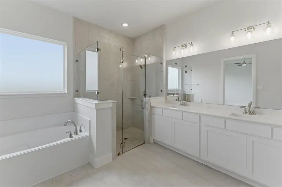 Bathroom featuring a freestanding tub, glass-enclosed shower, dual vanity with undermount sinks, and wall-mounted light fixtures