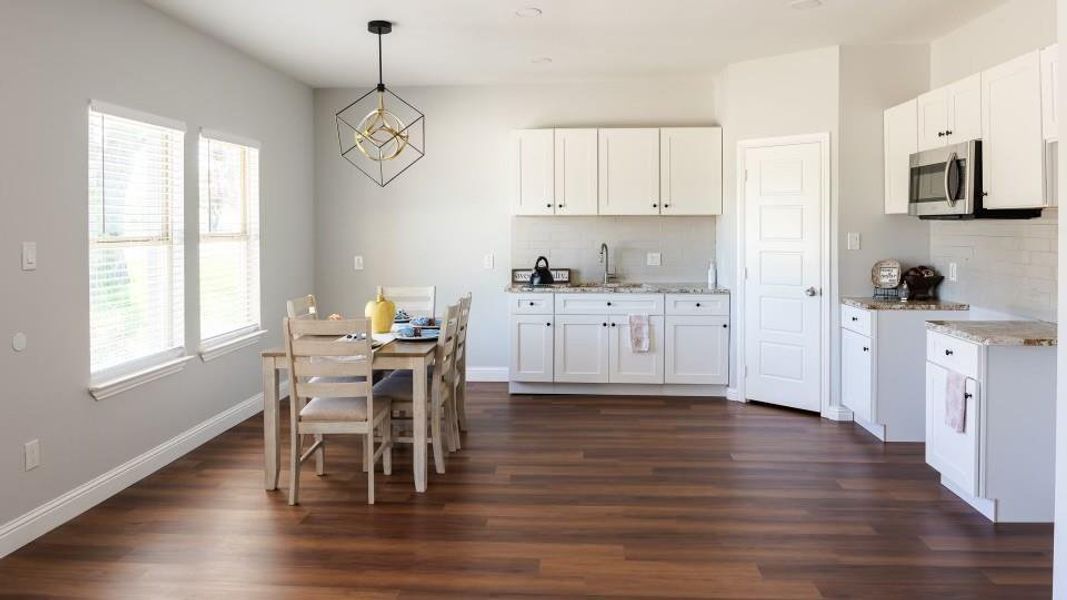 Kitchen with plenty of natural light, white cabinets, dark wood-type flooring, tasteful backsplash, and decorative light fixtures Kitchen with plenty of natural light, white cabinets, dark wood-type flooring, tasteful backsplash, and decorative light fixtures