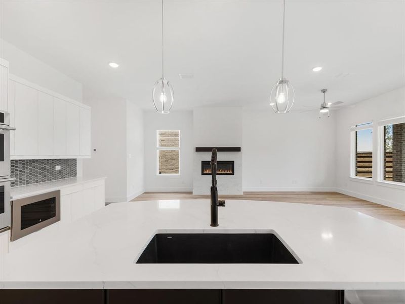 Kitchen with decorative light fixtures, open floor plan, light stone counters, and recessed lighting