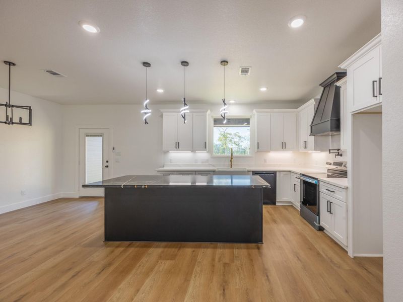 Crisp white cabinetry, quartz countertops, and black hardware create a clean and timeless look. The spacious island adds prep space and seating while stylish pendant lights offer a contemporary touch. Crisp white cabinetry, quartz countertops, and black hardware create a clean and timeless look. The spacious island adds prep space and seating while stylish pendant lights offer a contemporary touch.