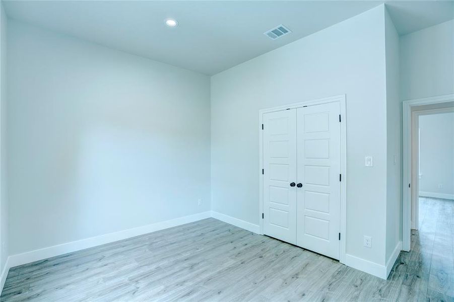 Interior room featuring wood-finish flooring, recessed lighting, and a double-door closet with black hardware