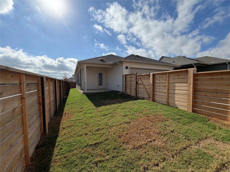 Back of house with a fenced backyard, a garage, and roof with shingles