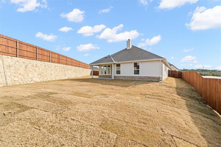 Rear view of property with a fenced backyard, a patio area, a chimney, and brick siding