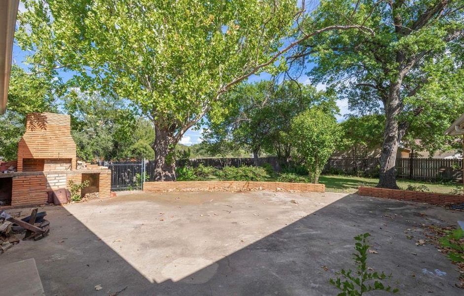 View of patio with an outdoor brick fireplace