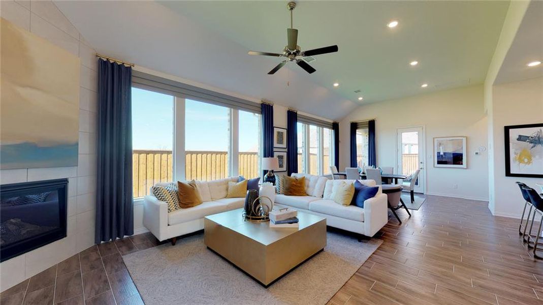 Living room featuring recessed lighting, wood tiled floors, a fireplace, vaulted ceiling, and ceiling fan