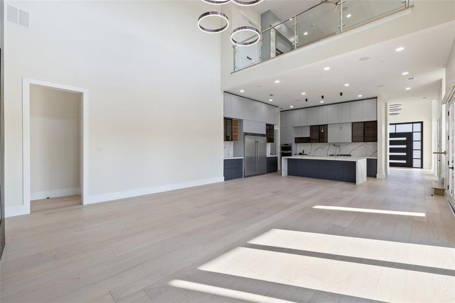 Unfurnished living room featuring light hardwood / wood-style flooring and a towering ceiling