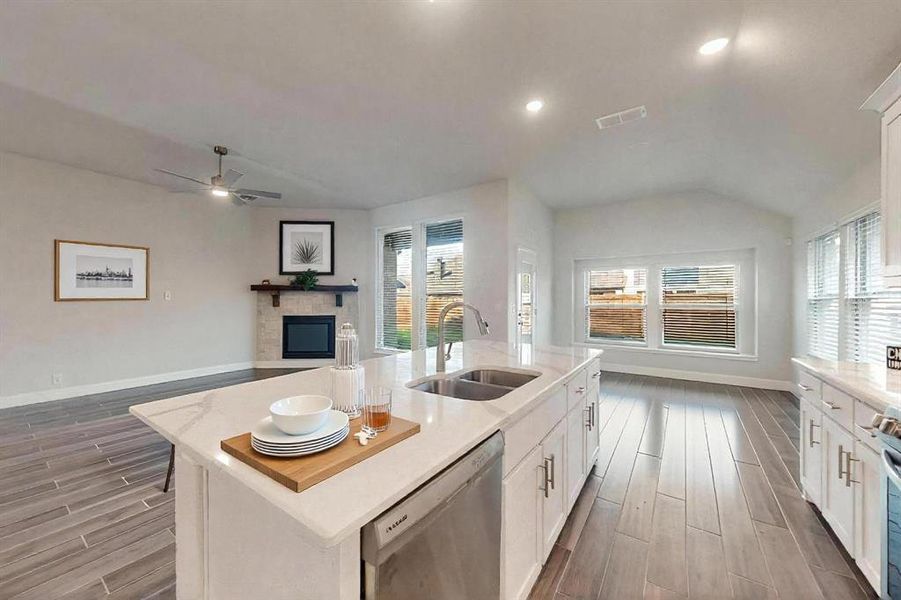 Kitchen with white cabinets, wood tiled floors, stainless steel appliances, light stone countertops, and a fireplace