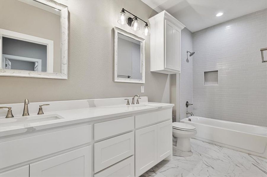 Full bathroom featuring tile patterned floors, vanity, tiled shower / bath combo, and toilet