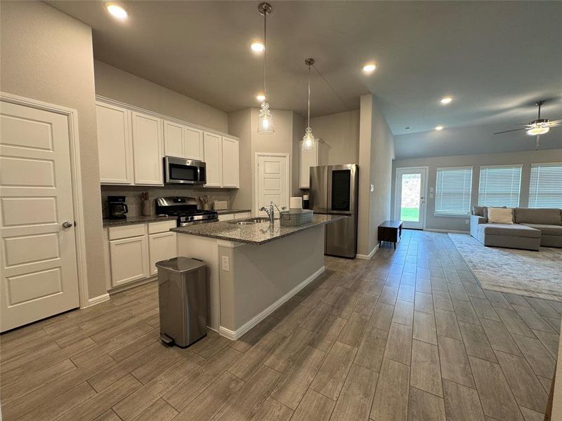 Kitchen featuring an island with a breakfast bar, stainless steel appliances, white cabinetry, and granite countertops Kitchen featuring an island with a breakfast bar, stainless steel appliances, white cabinetry, and granite countertops