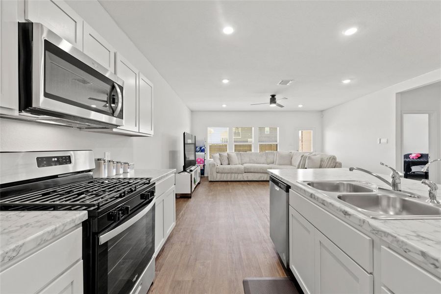 Chef’s Corner! This high-energy cooking station features a sleek gas range, a powerful built-in microwave, and crisp white cabinetry that keeps all your gourmet tools right at your fingertips.