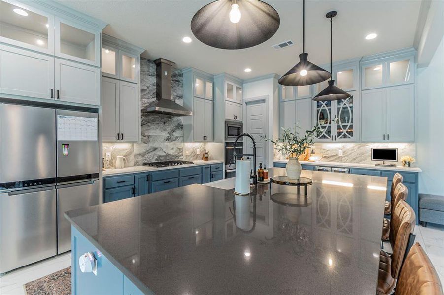 Kitchen with glass insert cabinets, stainless steel appliances, backsplash, and dark stone countertops Kitchen with glass insert cabinets, stainless steel appliances, backsplash, and dark stone countertops