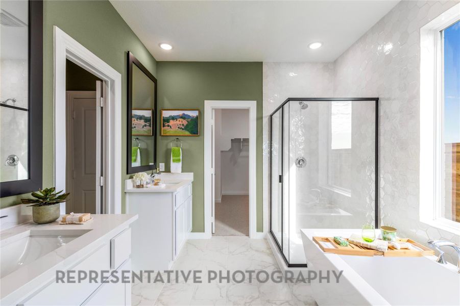 Full bathroom featuring a stall shower, two vanities, a soaking tub, marble finish floors, and healthy amount of natural light