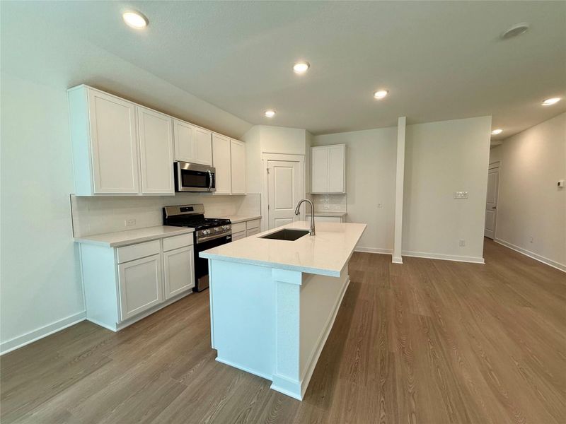 Kitchen with appliances with stainless steel finishes, white cabinetry, recessed lighting, light wood finished floors, and an island with sink Kitchen with appliances with stainless steel finishes, white cabinetry, recessed lighting, light wood finished floors, and an island with sink