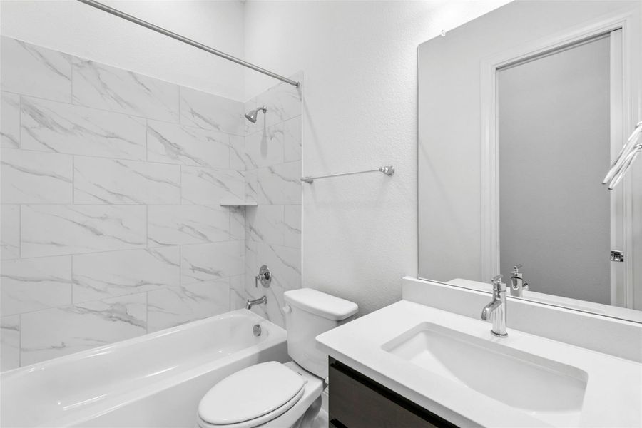 Modern bath with marble-patterned tile, a pristine bathtub, and a sleek vanity.