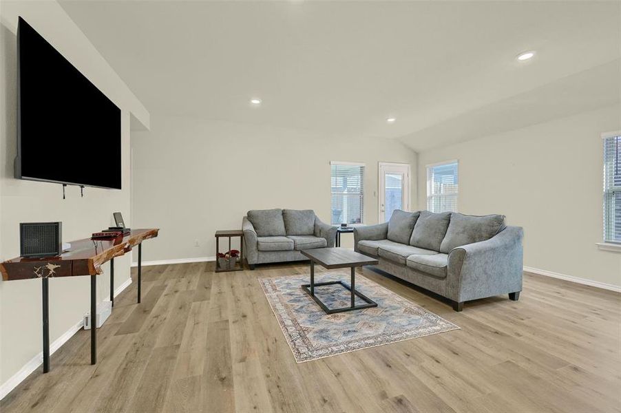 Living room with light wood-type flooring and vaulted ceiling