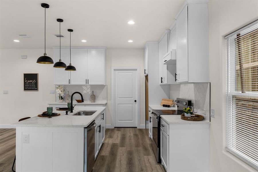 Kitchen with sink, a kitchen island with sink, stainless steel appliances, white cabinets, and decorative light fixtures