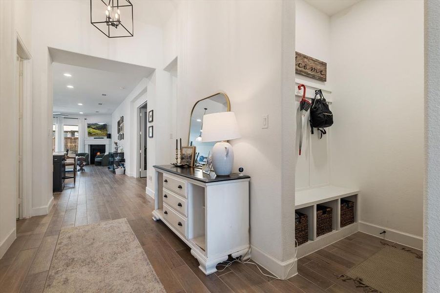 Corridor with wood-style flooring, recessed lighting, a vaulted ceiling, and a chandelier Corridor with wood-style flooring, recessed lighting, a vaulted ceiling, and a chandelier