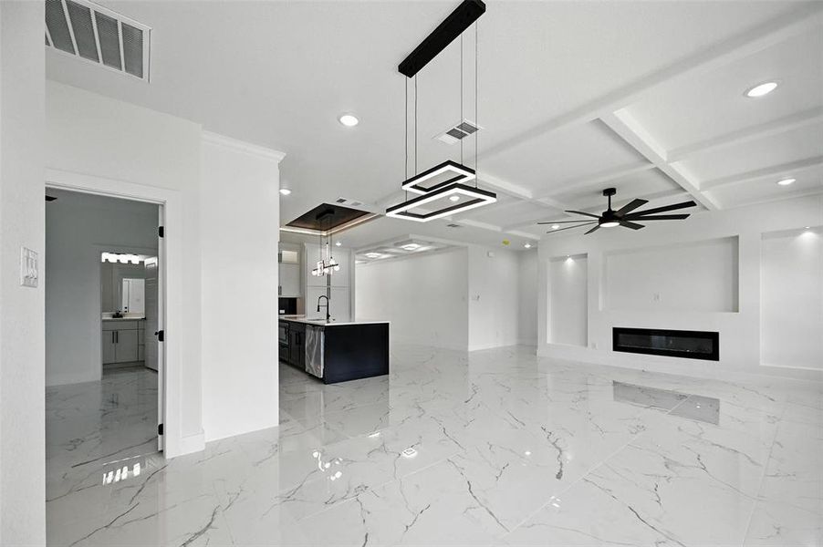 Unfurnished living room featuring recessed lighting, light marble finish floors, a glass covered fireplace, coffered ceiling, and beam ceiling