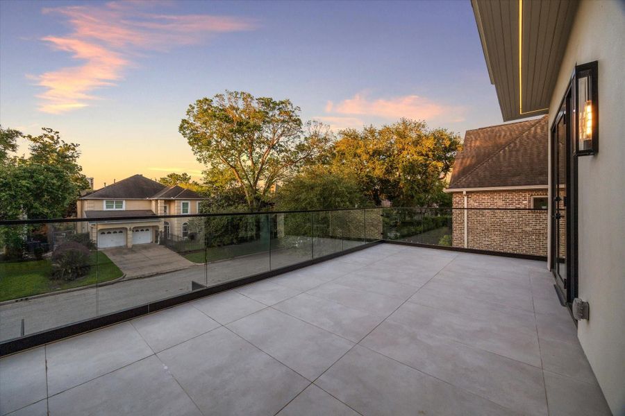 Guest bedroom private terrace with glass railing and front yard views