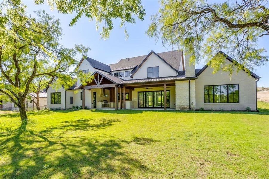Back of property featuring a patio area, a standing seam roof, a lawn, and ceiling fan