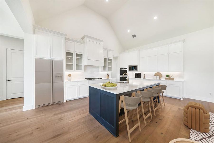 Kitchen featuring white cabinets, tasteful backsplash, a kitchen bar, glass insert cabinets, and white refrigerator with ice dispenser