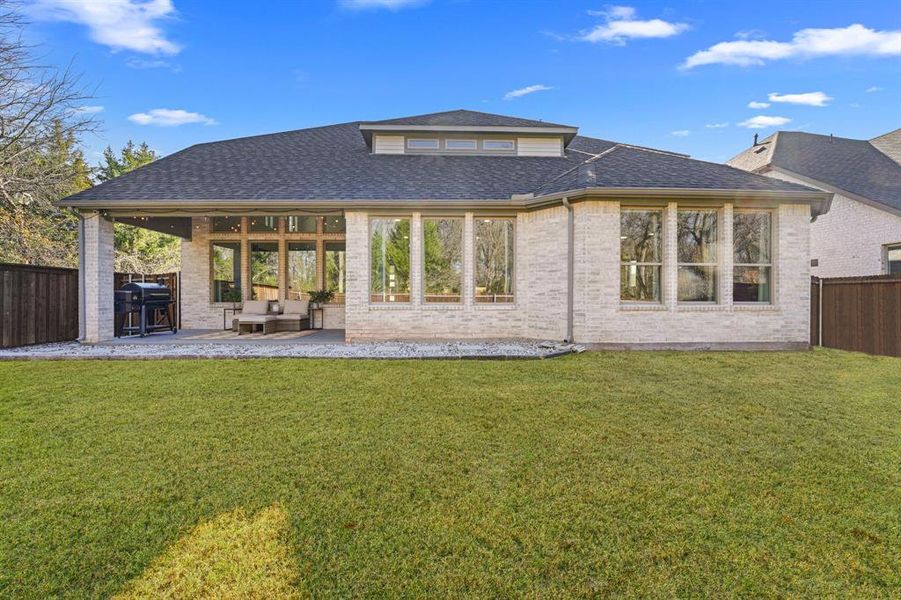 Back of property with a fenced backyard, a patio, a shingled roof, and brick siding