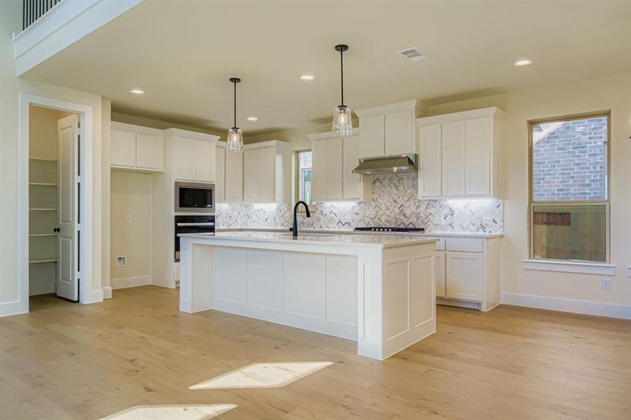 Kitchen with white cabinetry, backsplash, hanging light fixtures, and recessed lighting