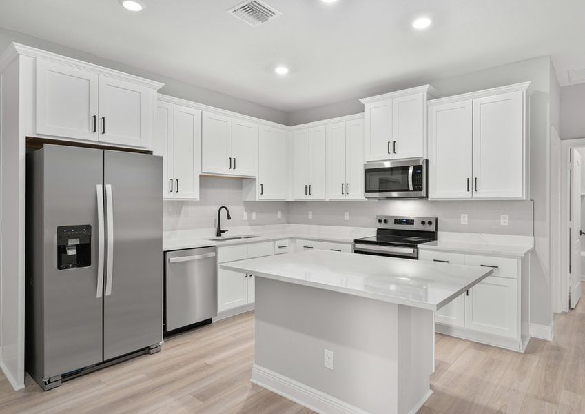 Kitchen with white cabinets, black hardware, quartz countertops and stainless steel appliances