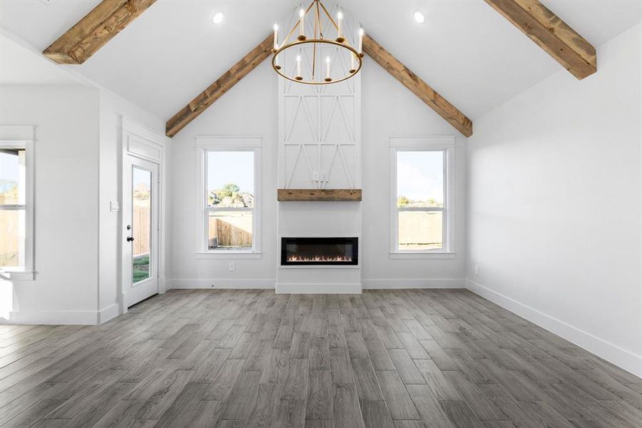 Unfurnished living room featuring beamed ceiling, dark hardwood / wood-style flooring, and high vaulted ceiling