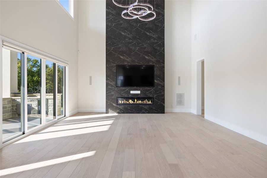 Unfurnished living room with a fireplace, a towering ceiling, and light hardwood / wood-style floors