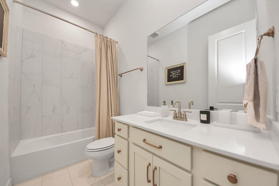 Elegant bathroom featuring a sleek vanity with modern fixtures, a spacious mirror, and a stylish bathtub with a marble-tiled shower area.