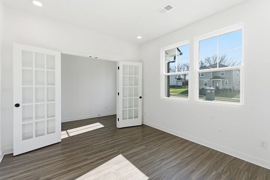 A room with a wood floor and a window with a view of a city.