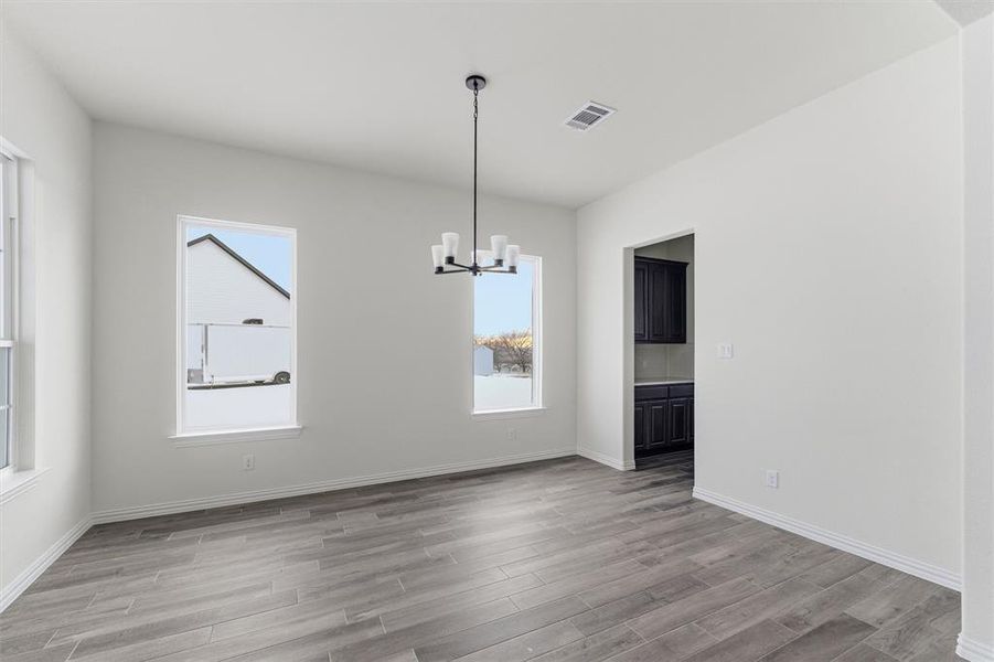 Unfurnished dining area featuring light wood finished floors, a chandelier, and healthy amount of natural light