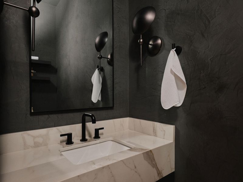 Bathroom vanity featuring a light-toned countertop with veining, an integrated rectangular sink, and a matte black three-piece faucet